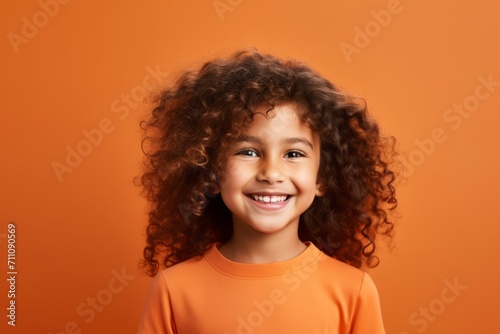 Portrait of smiling african american little girl over orange background © Iigo
