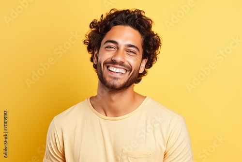 Portrait of a happy young latin man over yellow background. © Iigo