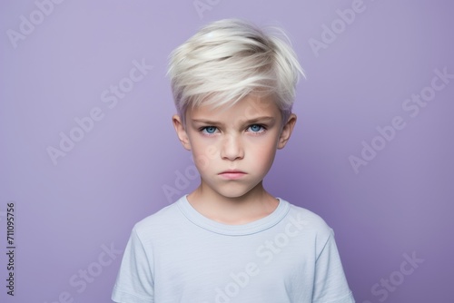 Portrait of a cute little boy with blond hair on a purple background