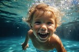 Ecstatic blonde toddler boy swimming underwater