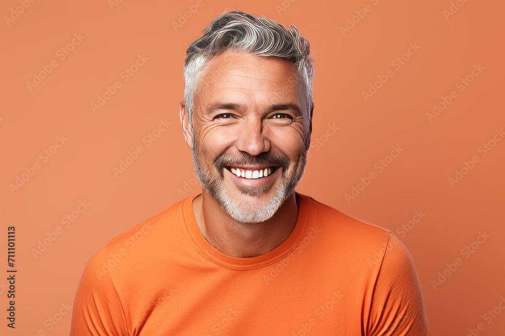 Portrait of smiling mature man in orange t-shirt on orange background Portrait of smiling mature man in orange t-shirt on orange background