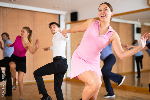 Cheerful young girl practicing vigorous lindy hop moves with male partner in dance class. Social dancing concept © JackF
