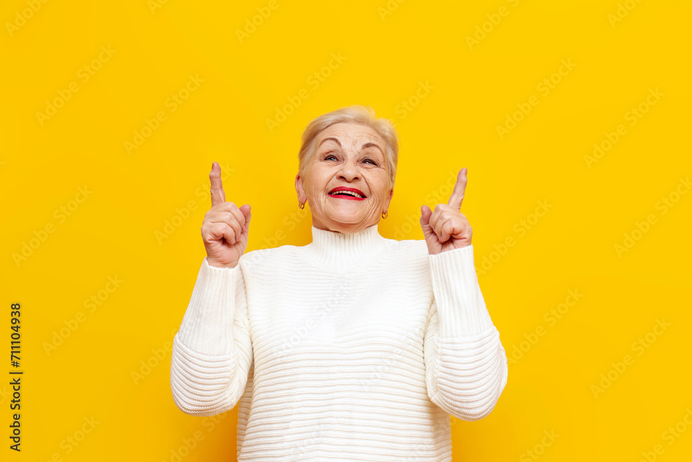 old cheerful grandmother with short hair smiling and pointing with her hands up on a yellow isolated background, elderly pensioner showing and advertising copy space old cheerful grandmother with short hair smiling and pointing with her hands up on a yellow isolated background, elderly pensioner showing and advertising copy space