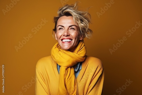 Portrait of happy woman in yellow sweater and scarf over yellow background © Iigo