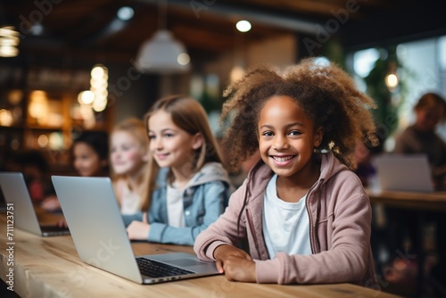 Portrait of a smiling African American girl sitting at a table and using a laptop computer