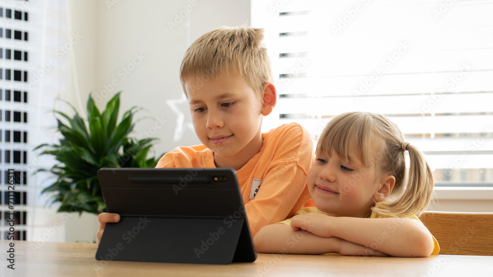 Cute brother and sister are happily looking at the tablet screen. Children and digital technologies Cute brother and sister are happily looking at the tablet screen. Children and digital technologies