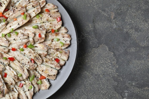 Tasty pickled anchovies with spices on grey textured table, top view. Space for text photo