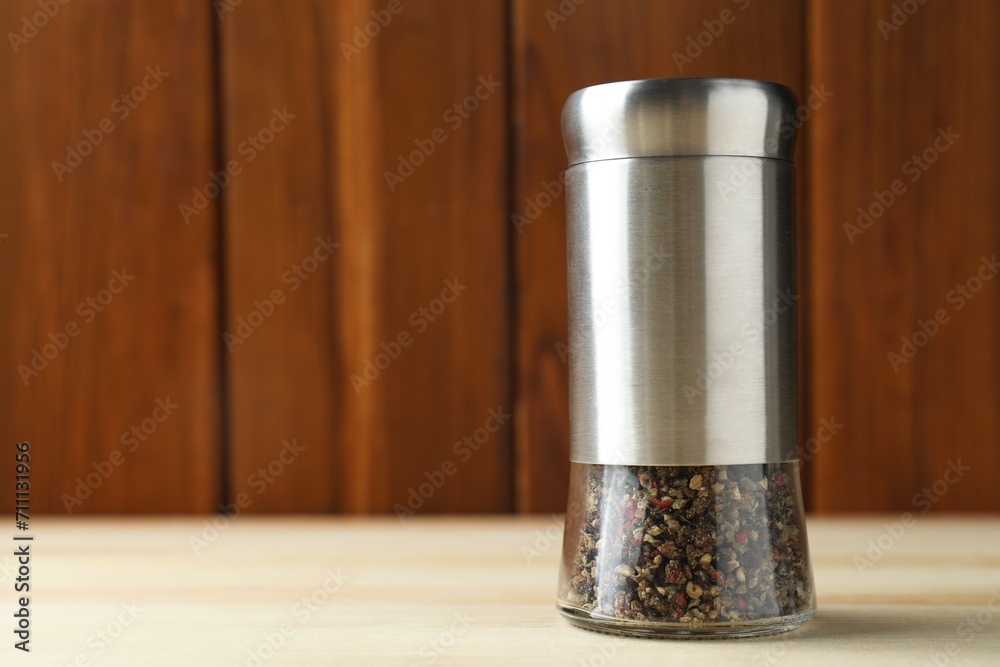 Pepper shaker on light wooden table, closeup. Space for text Pepper shaker on light wooden table, closeup. Space for text