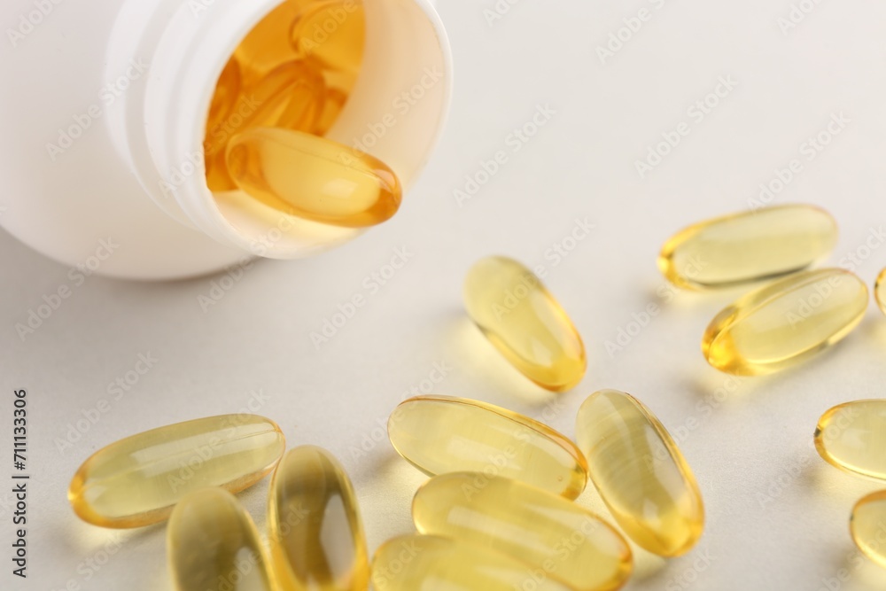 Vitamin capsules and bottle on light grey background, closeup Vitamin capsules and bottle on light grey background, closeup