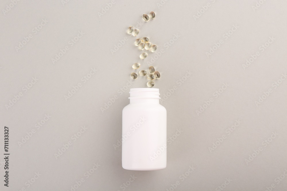 Bottle and vitamin capsules on light grey background, top view Bottle and vitamin capsules on light grey background, top view