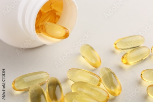 Vitamin capsules and bottle on light grey background, closeup