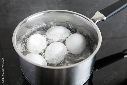 Chicken eggs boiling in saucepan on electric stove