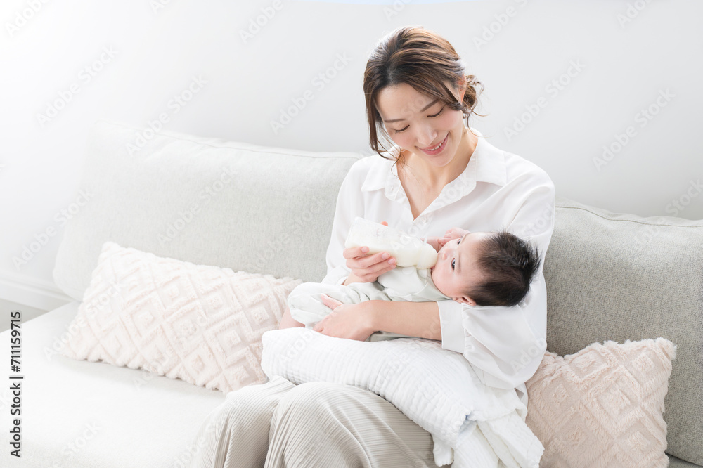 Cute and very precious woman sitting on the sofa feeding her baby. Cute and very precious woman sitting on the sofa feeding her baby.
