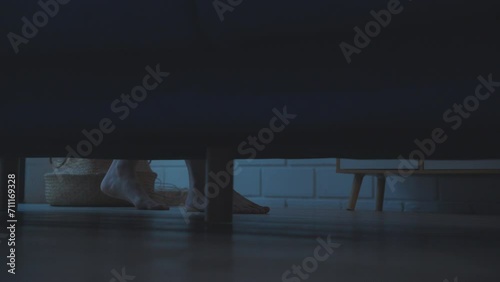 Shot of scary woman's feet walking under sofa in the darkn living room.  photo