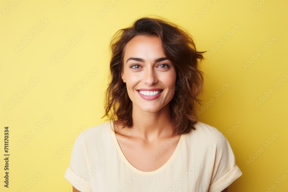 Portrait of happy smiling young woman looking at camera over yellow background Portrait of happy smiling young woman looking at camera over yellow background