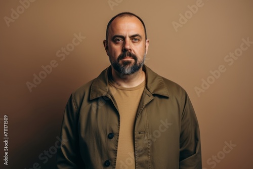 Portrait of a bearded man in a green jacket, looking at the camera.