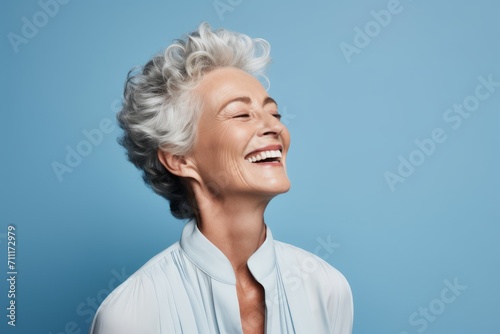 Cheerful senior woman posing on blue background. Beauty, fashion.