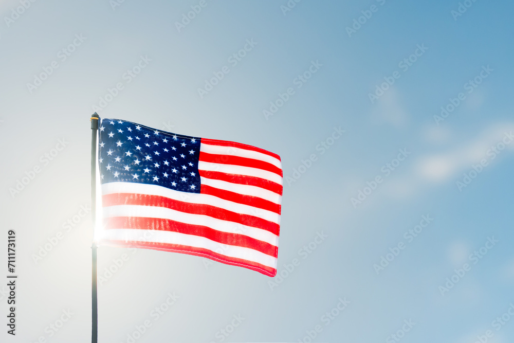 Pride and Patriotism. American flag unfurled against the sunlight and blue sky.