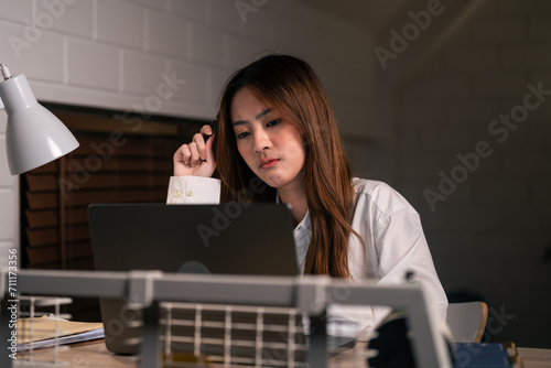Depressed Asian young woman overworking during bed time at night. 