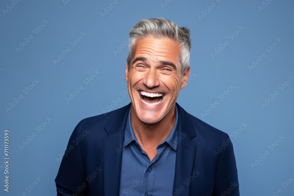 Handsome mature man laughing and looking at camera on blue background Handsome mature man laughing and looking at camera on blue background