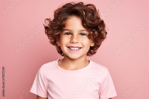Portrait of a smiling little girl with curly hair on a pink background © Inigo