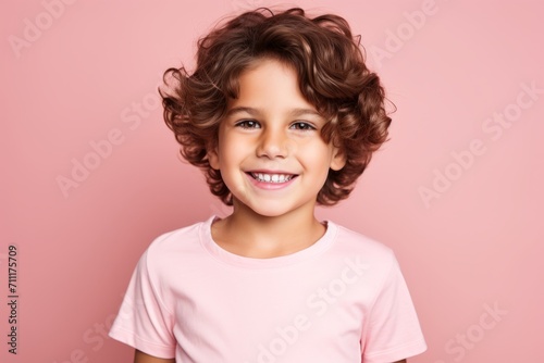 Portrait of a smiling little girl with curly hair on a pink background