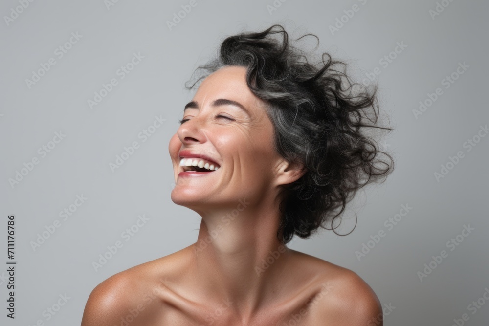Portrait of a happy young woman laughing and looking up over gray background Portrait of a happy young woman laughing and looking up over gray background