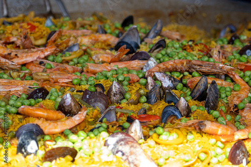 Mexican paella with several ingredients (rice, shrimp, peas, shellfish and tomato) being made in a large wok_2.