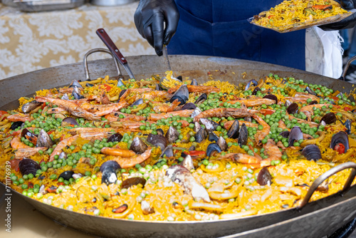 Mexican paella with several ingredients (rice, shrimp, peas, shellfish and tomato) being made in a large wok_1.