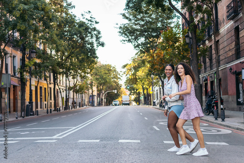 Two girls crossing the pedestrian crossing in the city.