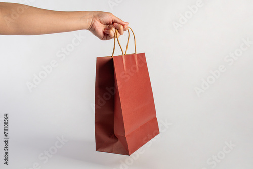 Red paper shopping bag in hand on white background.