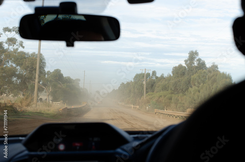 Car Front Window View with dust cloud on a gravel road. Exploring Remote Areas, Australian Outback Adventure, Unsealed Road Exploration, and Off-Grid Journey Concept. Cobram VIC Australia