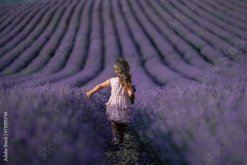 Fototapeta Naklejka Na Ścianę i Meble -  Lavender field girl. Back view happy girl in pink dress with flowing hair runs through a lilac field of lavender. Aromatherapy travel