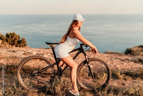A woman cyclist on a mountain bike looking at the landscape sea. Adventure travel on bike.