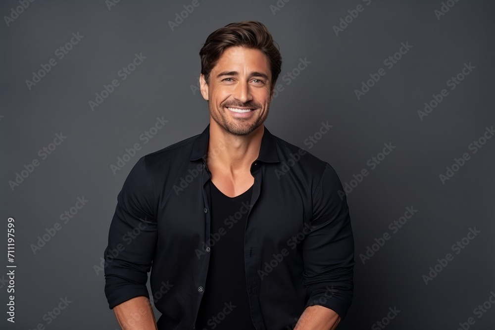 Portrait of a handsome young man smiling at the camera while standing against grey background Portrait of a handsome young man smiling at the camera while standing against grey background