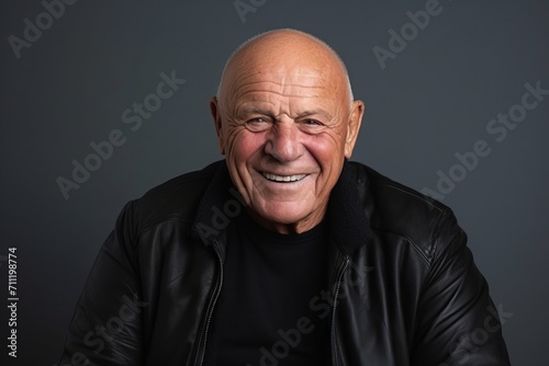 Portrait of an old man laughing while wearing a leather jacket.