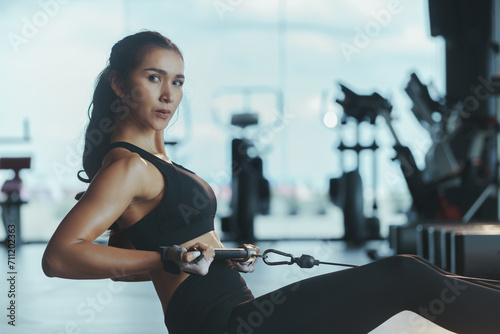 Sporty woman exercising on multistation at gym for arm and shoulders muscles. Fitness exercising in gym.