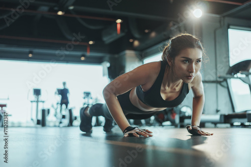 Sporty woman performing push-ups from the floor in the gym.