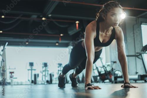 Sporty woman performing push-ups from the floor in the gym.
