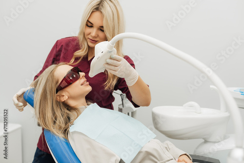 The doctor performs a professional teeth whitening procedure with an ultraviolet lamp.