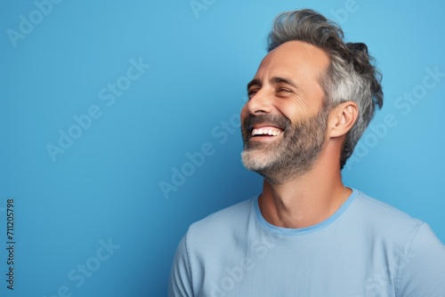 Portrait of a happy mature man with grey hair and beard on blue background
