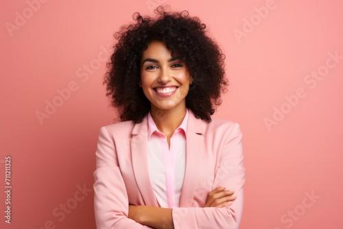 Portrait of smiling african american businesswoman with crossed arms over pink background