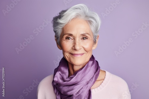 Portrait of smiling senior woman with violet scarf on violet background.