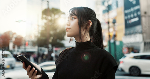 Walking, cellphone and Japanese woman in the city networking on social media or the internet. Phone, adventure and young female person commuting for travel in road of urban town in Kyoto Japan.