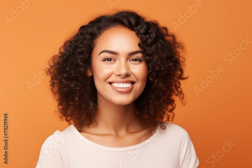 Portrait of young happy smiling african american woman, over orange background © Inigo