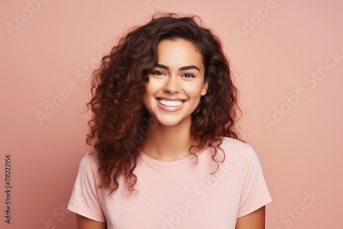 Portrait of happy smiling young woman with long curly hair over pink background