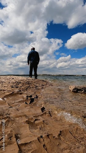 Standing on the rocky shoreline of Glendo Reservoir on a cool day. He watches in the distance as fishermen try their luck. Near Glendo Wyoming in the United State on May 2022.  photo