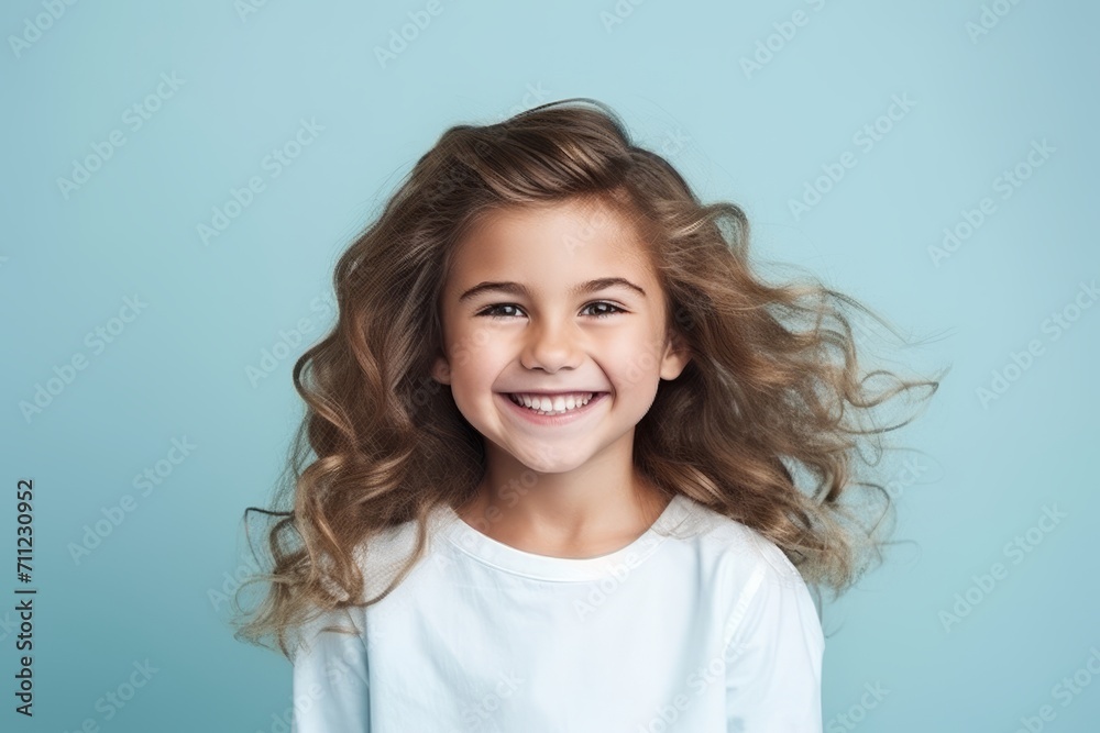 Portrait of a smiling little girl with long curly hair over blue background Portrait of a smiling little girl with long curly hair over blue background