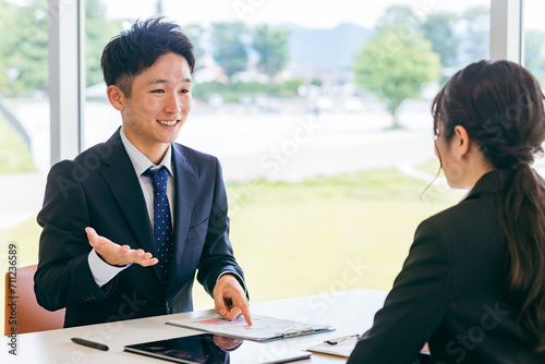 スーツ姿の女性と打ち合わせをするアジア人ビジネスマン（面談・ヒアリング・営業）
 photo