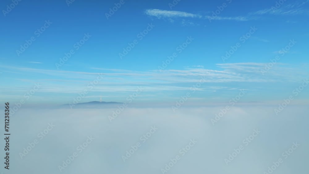 Aerial video: Drone flies backward, revealing a lone skyscraper amidst thick clouds on the left. Capturing the cityscape in reverse, it showcases the building in a cinematic view. LuPa Creative.